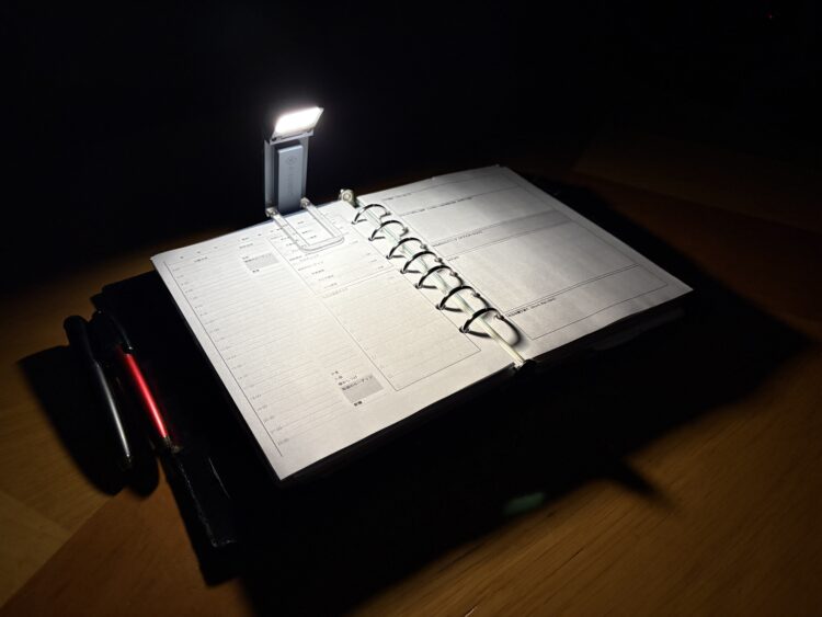 暗闇でglocusent upgrated bookmark book lightの暖色光2700K(25ルーメン)でA5サイズの見開き手帳を照らした様子